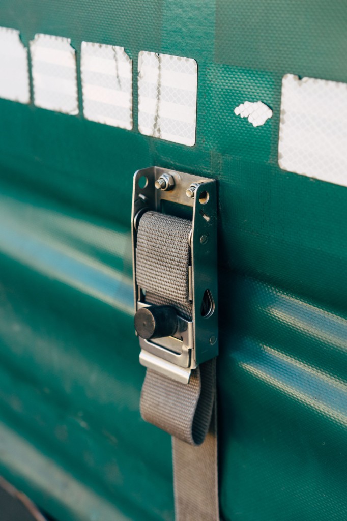 Industrial cargo buckle and webbing on a muted teal surface — a constraint designed to hold under pressure.